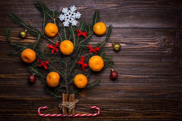 Albero di Natale decorato con mandarini e palline regali su uno sfondo di legno