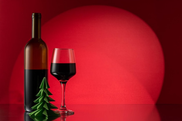 Albero di Natale di carta verde con bottiglia di vino rosso e bicchiere di vino Anno nuovo o sfondo di Natale