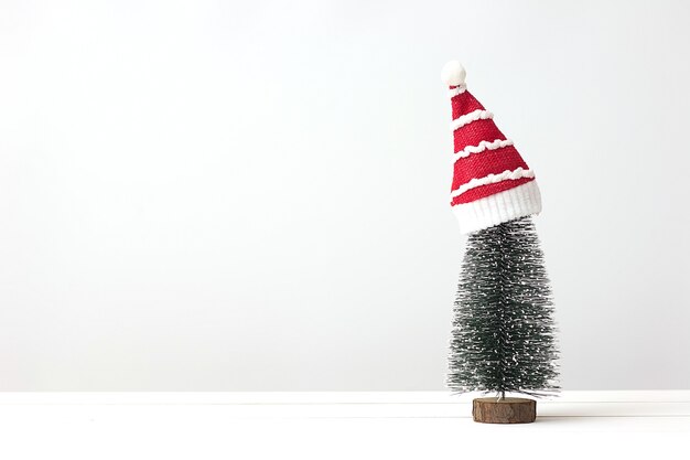 Albero di Natale e cappello di Babbo Natale su tavola di legno bianco con spazio di copia. Concetto di vacanza di Natale.