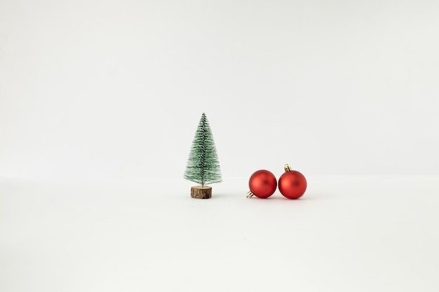 Albero di Natale e due palline rosse su sfondo bianco Concetto minimo di Capodanno