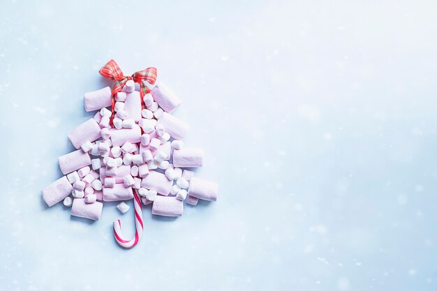 Albero di Natale fatto di marshmallow rosa e bastoncino di zucchero con effetto neve