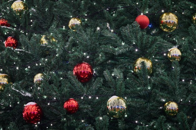 Albero di Natale festivo di Capodanno decorato con palle di Natale gialle rosse con ghirlande di luci