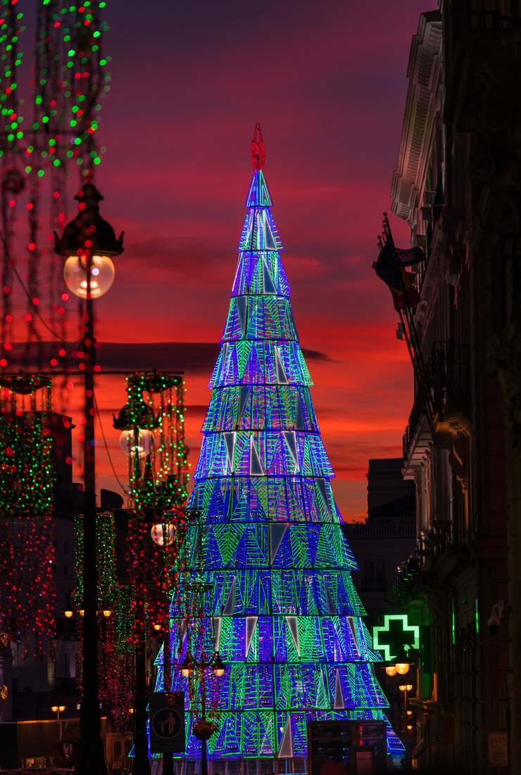 Albero di Natale illuminato che sorge nel centro della piazza Puerta del Sol a Madrid al crepuscolo.