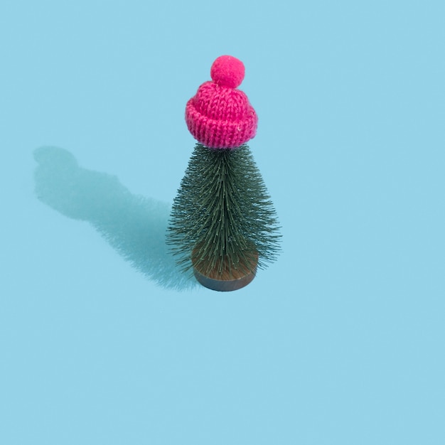 Albero di Natale in berretto invernale rosa pastello su sfondo blu