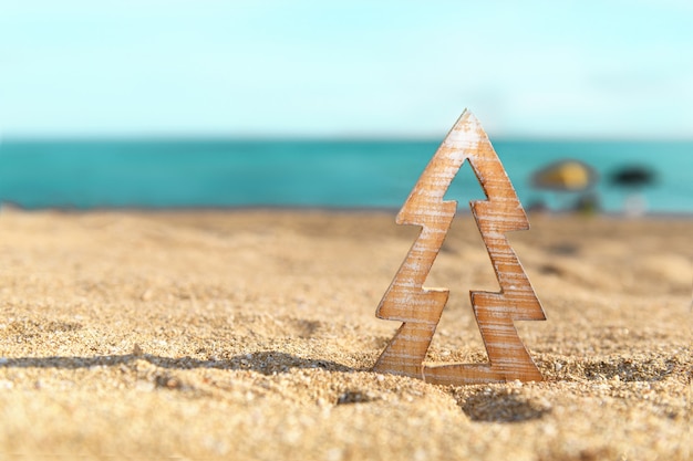 Albero di Natale in legno di legname su una sabbia sulla spiaggia tropicale vicino all'oceano, Natale estivo