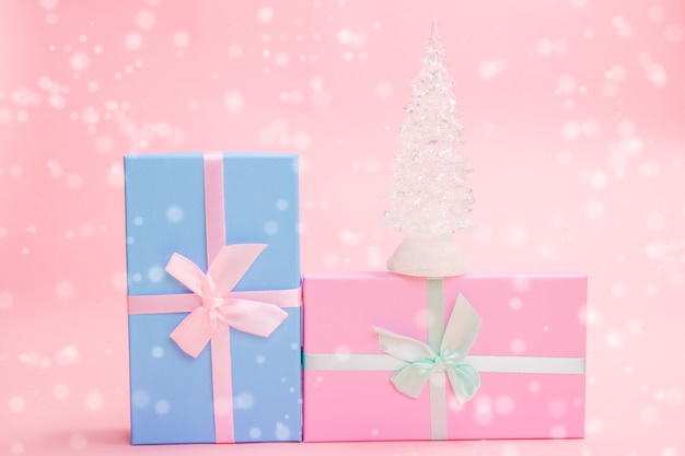 Albero di Natale in vetro bianco con regali con fiocchi su sfondo rosa