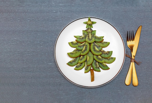 Albero di Natale kiwi commestibile su un piatto bianco