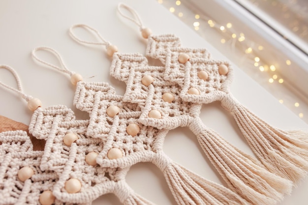 Albero di Natale macrame giocattoli su papper artigianale Sfondo bianco Materiali naturali filo di cotone perline di legno e bastoncino Decorazioni ecologiche ornamenti decorazioni fatte a mano Vacanze invernali e capodanno