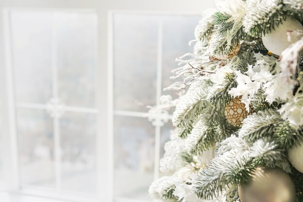 Albero di Natale pieno di decorazioni e giocattoli alla finestra luminosa.