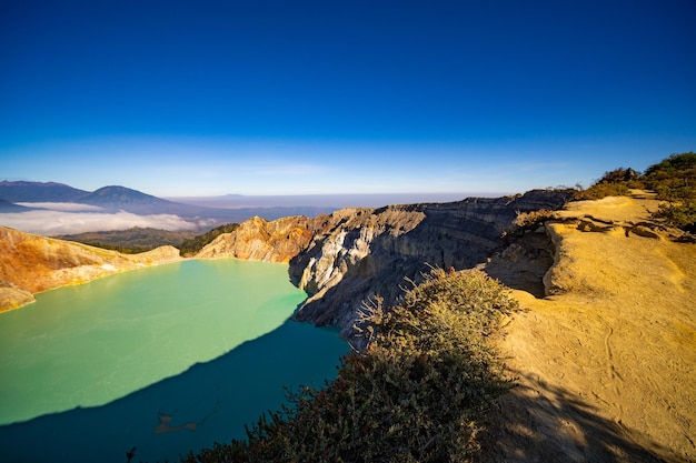 Albero senza foglie di legno morto con lago d'acqua turchese Natura bellissima Paesaggio montagna e lago verde al vulcano Kawah Ijen Java orientale Indonesia