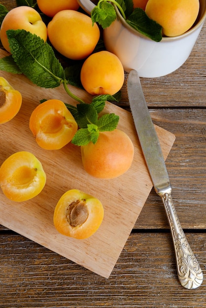 Albicocche mature con foglie di menta verde sul tagliere su fondo di legno