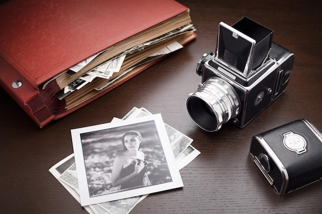 Album fotografico rosso con vecchie foto e fotocamera di medio formato su tavola di legno