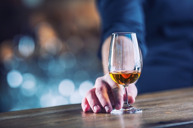 Alcolismo. Mano alcolica o barman e bere il distillato brandy o cognac.