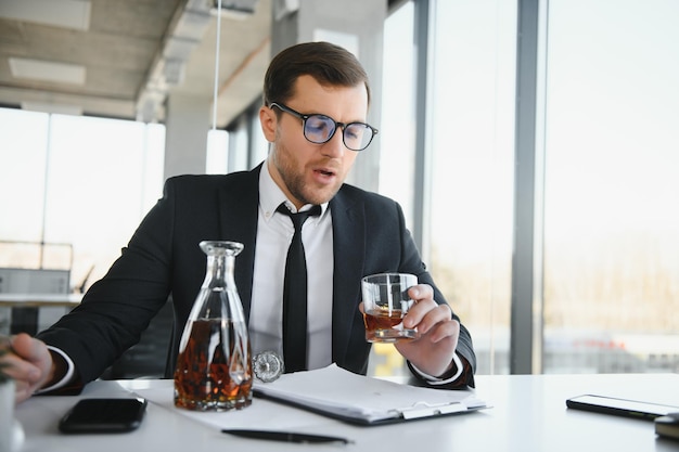 Alcolismo sul lavoro Dipendente stanco che beve alcol sul posto di lavoro non può gestire lo stress