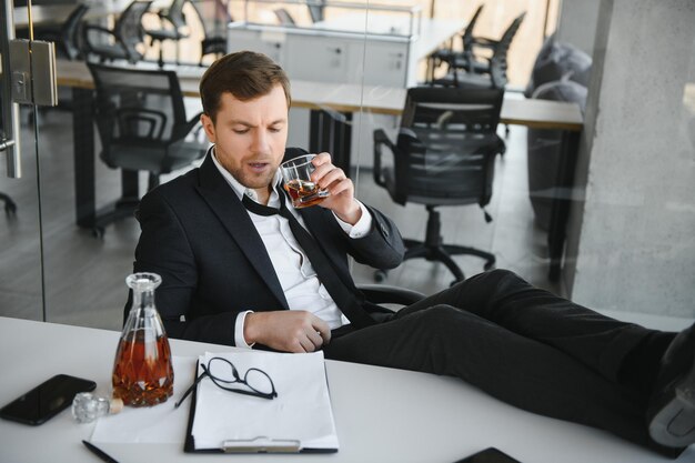 Alcolismo sul lavoro Dipendente stanco che beve alcol sul posto di lavoro non può gestire lo stress