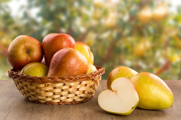 Alcune pere in un cesto su una superficie di legno. Frutta fresca