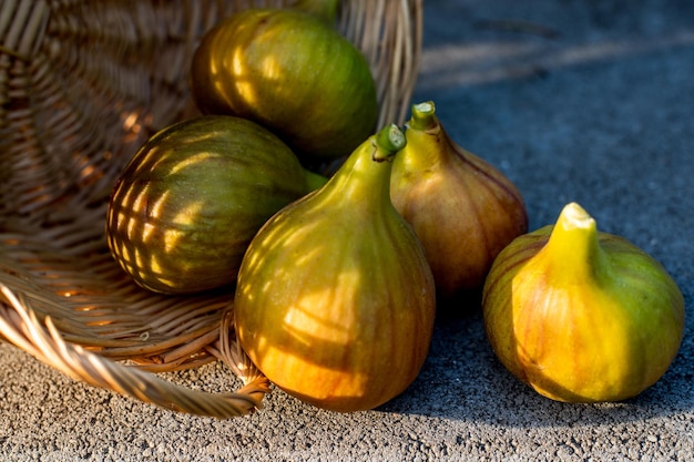 Alcuni fichi in un cesto di viti su uno sfondo di cemento al sole