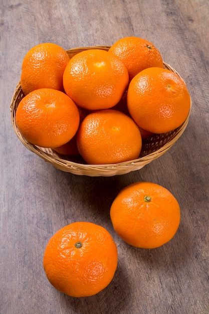 Alcuni mandarini in un cesto su una superficie di legno. Frutta fresca