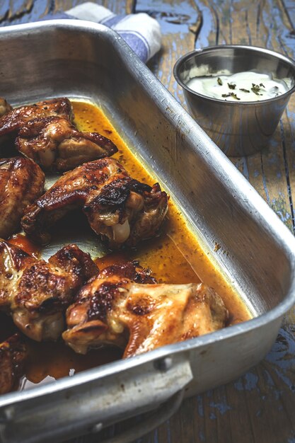 Alette di pollo arrosto fatte in casa nella teglia sul tavolo di legno