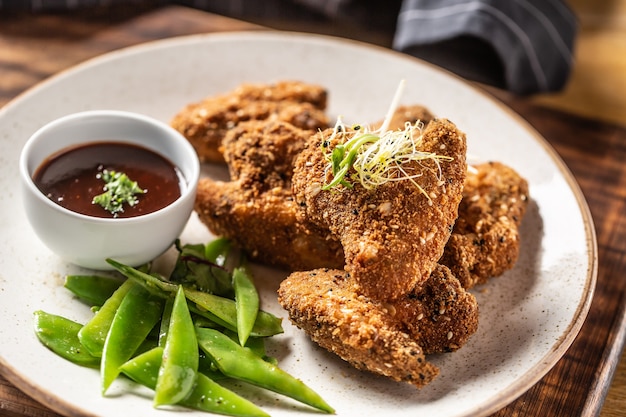 Alette di pollo fritte con piselli zuccherati ed erbe aromatiche.