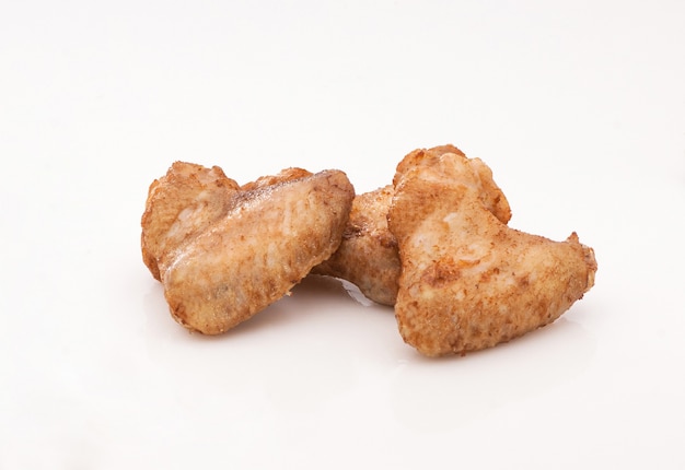 Alette di pollo fritte in olio su fondo bianco con riflesso