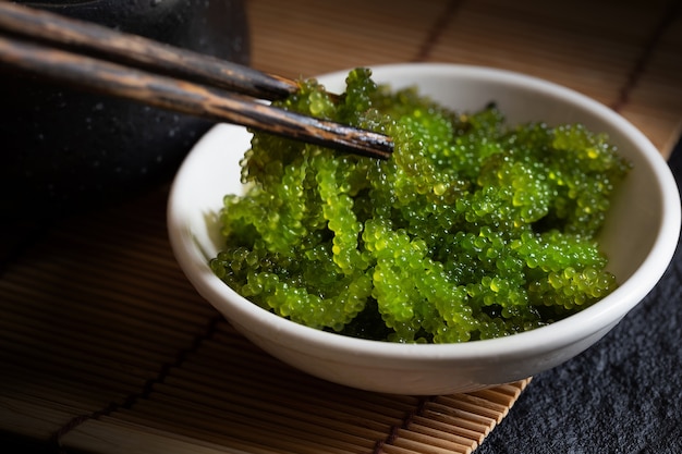 Alga ovale dell&#39;uva di mare, caviale verde vicino su fondo scuro