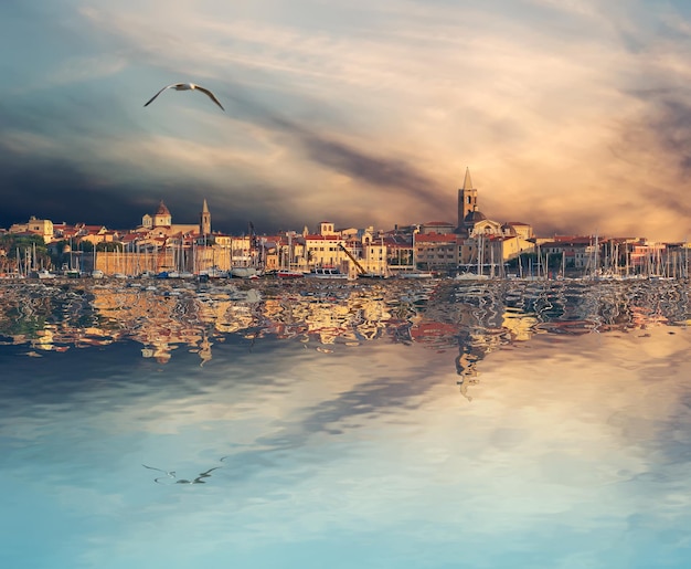 Alghero si riflette sull'acqua al tramonto