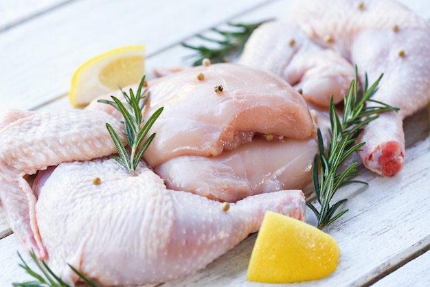 Ali di petto e zampe di pollo crudo crudo marinato con ingredienti per cucinare - Pollo crudo fresco con erbe aromatiche al limone e rosmarino