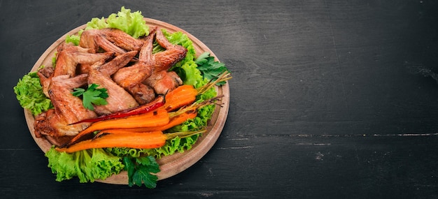 Ali di pollo alla griglia con verdure e carote su sfondo di legno Vista dall'alto Spazio di copia