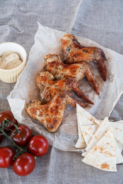 Ali di pollo alla griglia piccanti pronte con verdure e pomodoro concetto di riposo estivo