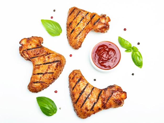 Ali di pollo arrostite, spezie rosse del basilico dei pomodori della salsa del bbq su bianco