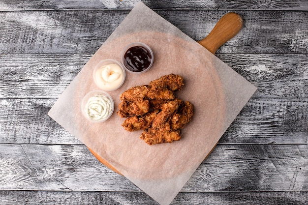 Ali di pollo con tre salse su fondo di legno bianco