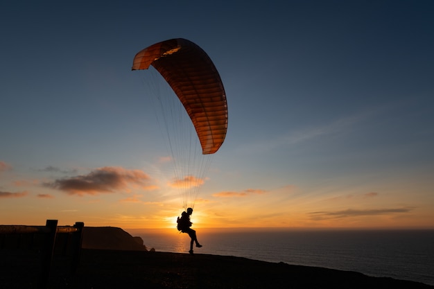 Aliante che sorvola la riva di mare al tramonto. Sport in parapendio