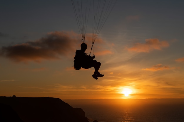 Aliante che sorvola la riva di mare al tramonto. Sport in parapendio