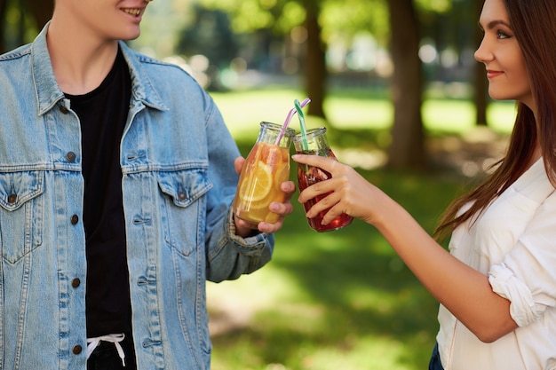 Alimentazione sana. Amici che bevono succo di disintossicazione fresca sullo sfondo della natura verde green