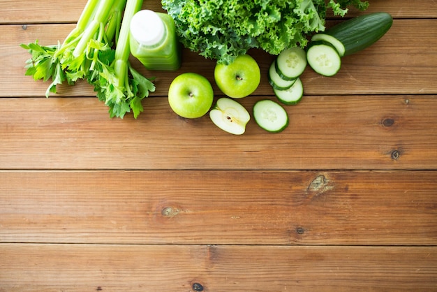 alimentazione sana, cibo, dieta e concetto vegetariano - bottiglia con succo verde, frutta e verdura sul tavolo di legno