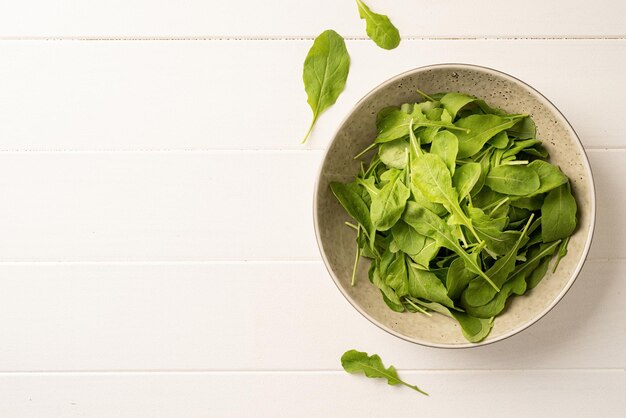 Alimentazione sana e dieta Foglie di rucola fresca in una ciotola bianca su sfondo di legno vista dall'alto piatto