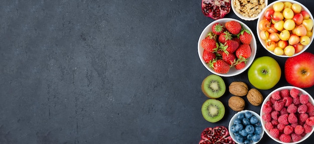 Alimenti ad alto contenuto di antiossidanti: bacche, noci, frutta. Sfondo di cemento nero. Copia spazio.