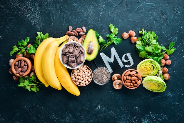 Alimenti contenenti magnesio naturale Mg Cioccolato banana noci di cacao avocado broccoli mandorle Vista dall'alto su sfondo nero