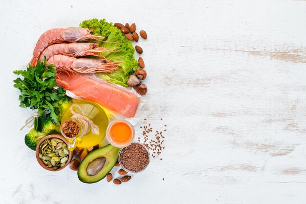 Alimenti contenenti omega 3 Vitamina Alimenti sani avocado pesce gamberetti broccoli noci di lino uova prezzemolo Vista dall'alto Spazio libero per il testo Su uno sfondo di legno bianco