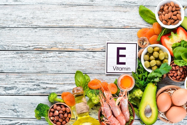 Alimenti contenenti vitamina E naturale: spinaci, prezzemolo, gamberetti, semi di zucca, uova, avocado, broccoli. Vista dall'alto. Su uno sfondo di legno bianco.