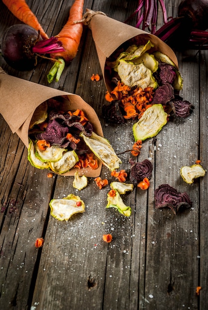 Alimenti dietetici biologici La dieta vegana Verdure Secche Patatine fatte in casa da barbabietole, carote e zucchine. Sul vecchio tavolo di legno rustico, con verdure fresche. copyspace