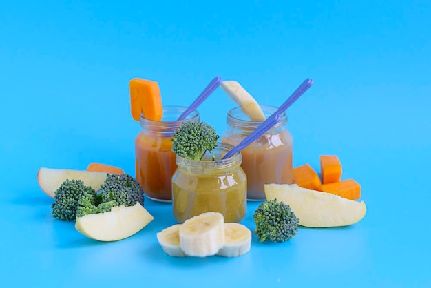 Alimenti per bambini di frutta e verdura in vasetti di vetro su sfondo blu, copia spazio cibo sano per bambini