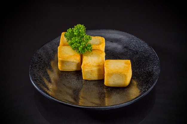 Alimento asiatico, tofu fritto del pesce su fondo nero, alimento tradizionale giapponese