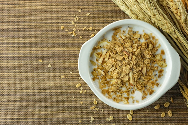 Alimento e fiocchi di latte dell&#39;alimento di mattina in ciotola bianca sulla tavola di legno.