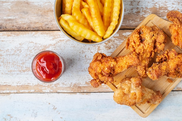 Alimento e patate fritte di pollo fritto su una tavola di legno