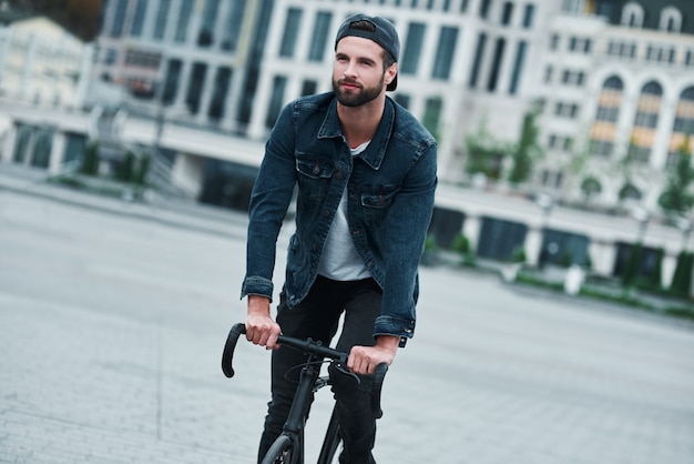 All'aperto per il tempo libero giovane uomo elegante sulla strada della città in bicicletta sorridente felice