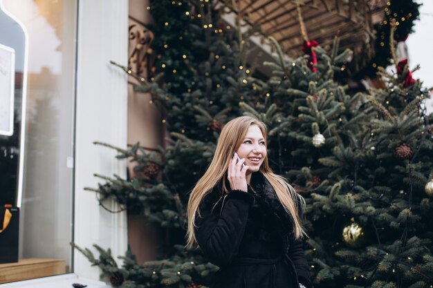 All'aperto vicino sul ritratto della donna con lo smartphone nelle decorazioni di natale