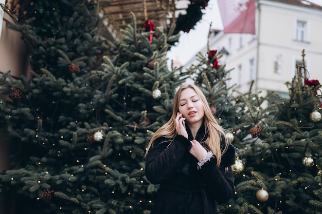 All'aperto vicino sul ritratto della donna con lo smartphone nelle decorazioni di natale