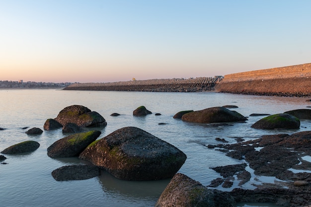 All'imbrunire il mare della costa schiaffeggiava gli scogli